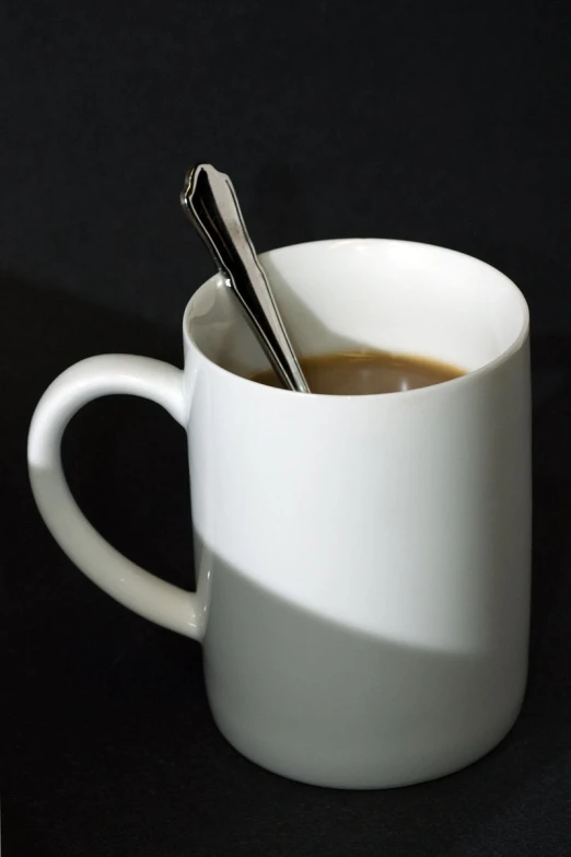 the cup has two spoons in it on the table