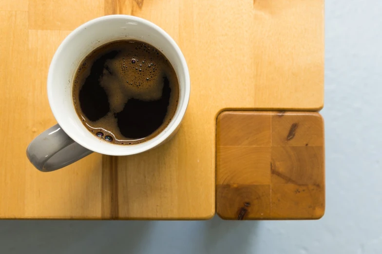 a cup of black coffee sitting on a wooden table