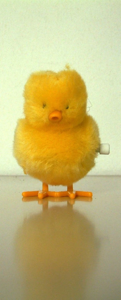 a little yellow chick bird sitting on top of a wooden table