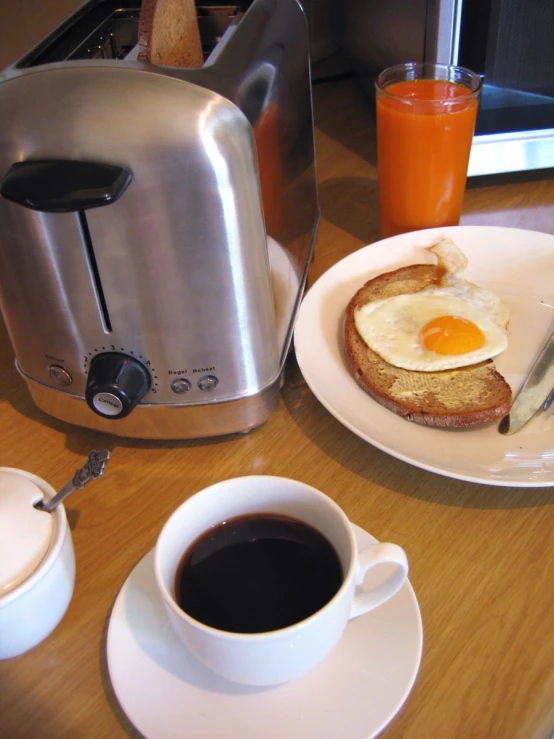 a toaster sitting on a counter with coffee, a bowl of cereal and an egg on it