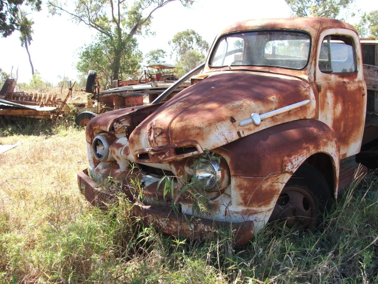 an old truck is parked in some tall grass