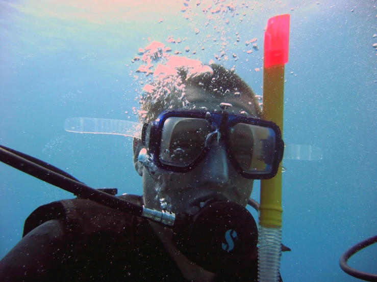 a man in black wetsuit holding onto a yellow tube