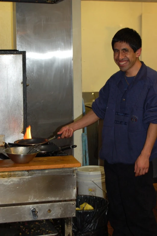 a smiling man uses an oil stove in the kitchen