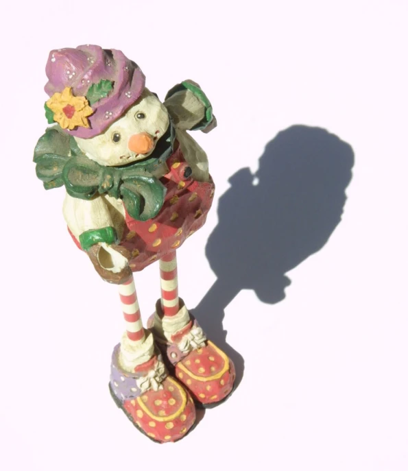 a clay figurine of a snow girl holding onto her shoes