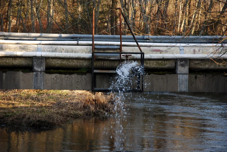 a small waterfall in the middle of a river near a street sign