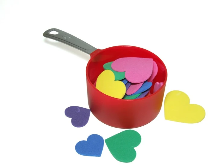 small plastic hearts sit in a cup filled with colorful heart stickers