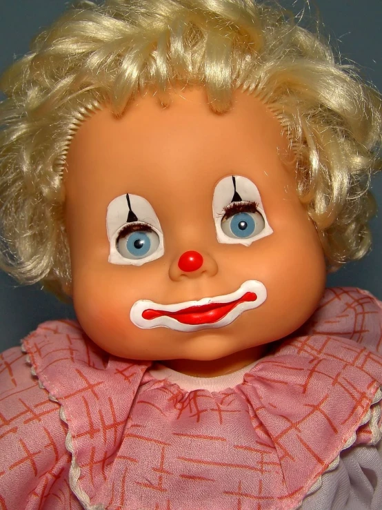 a doll with blonde hair has blue eyes and is wearing a clown mask