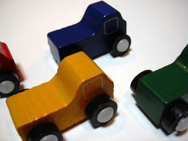 three wooden toy cars and one is orange, green and red