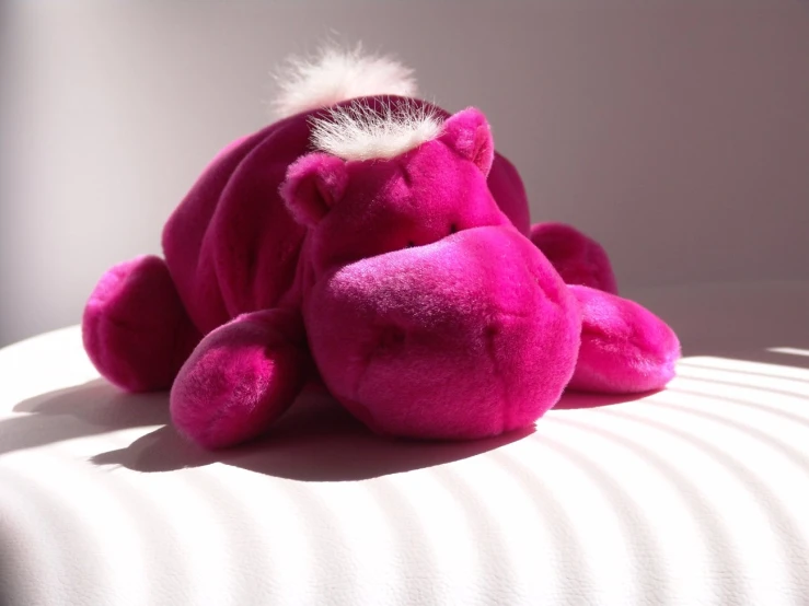 a pink toy sitting on top of a bed