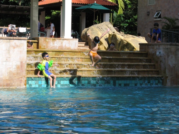 a boy and girl are jumping into a swimming pool