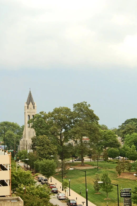 a very large church tower towering over a lush green park