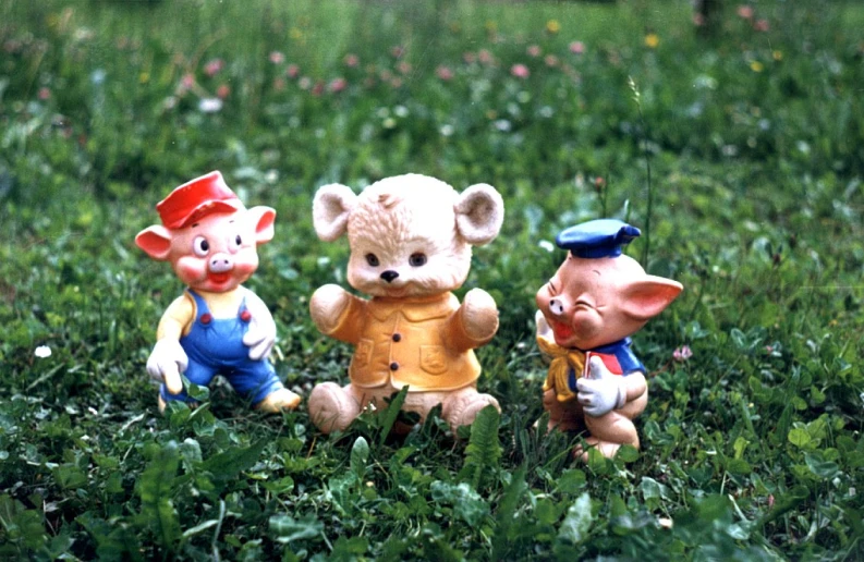 three little ceramic pigs wearing hats in the grass