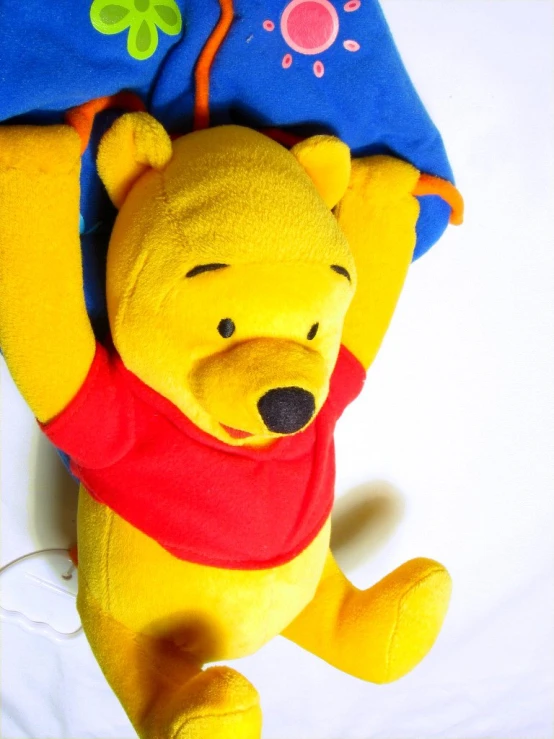 a yellow winnie the pooh plush toy lying on a white surface