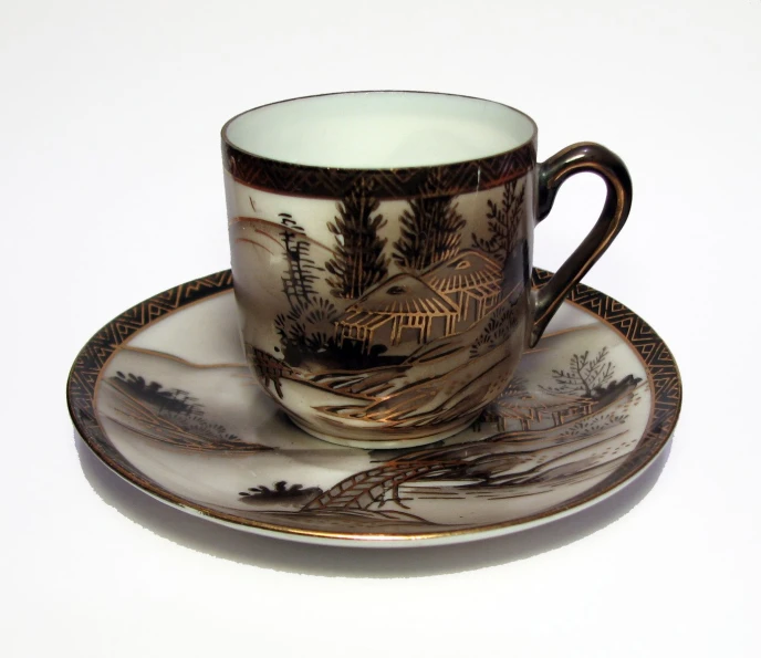 a teacup and saucer with a bird design on the side