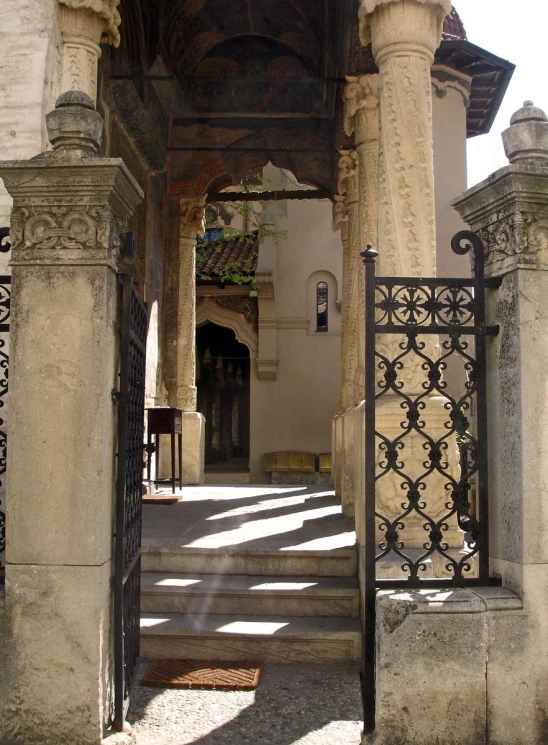 a small archway between two stone buildings with iron railings