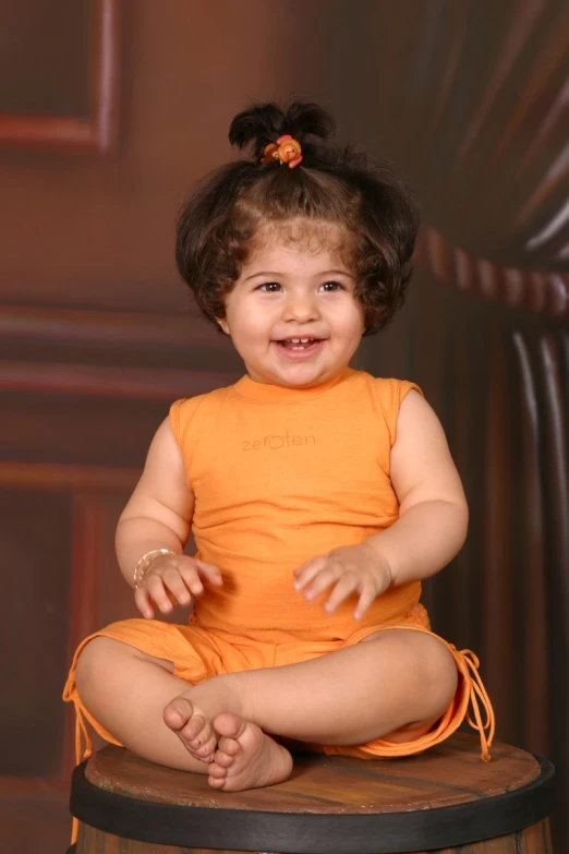 a small child smiling on top of a barrel