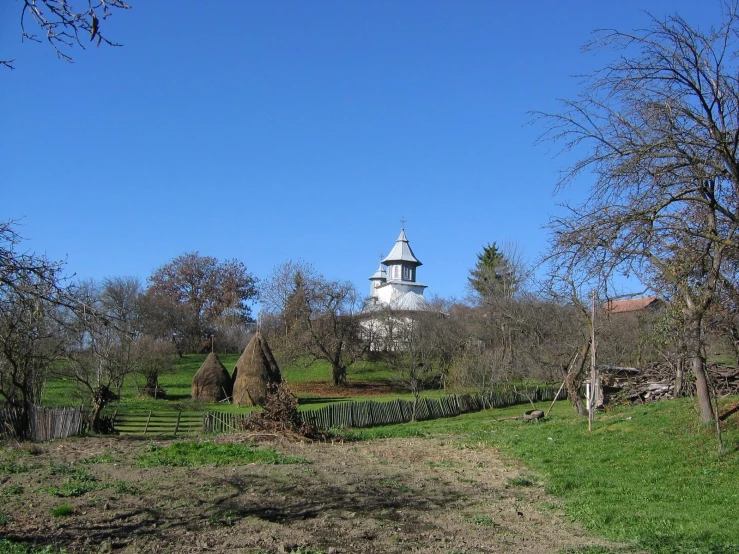 a white and black church on a hill surrounded by trees