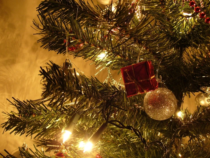 a lit christmas tree with presents hanging on it