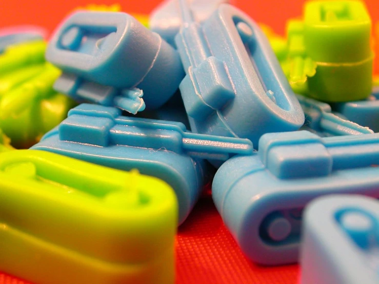 blue and green plastic children's toy cars are sitting on a bright red surface