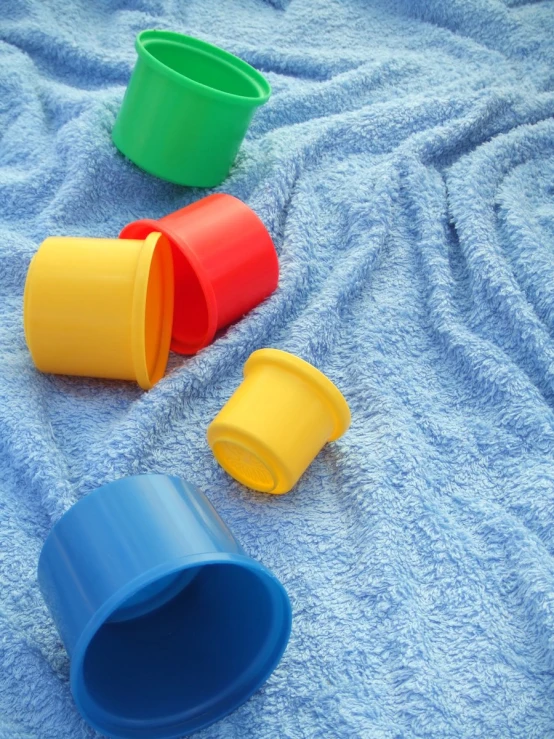 several colorful cups lined up on top of a blanket