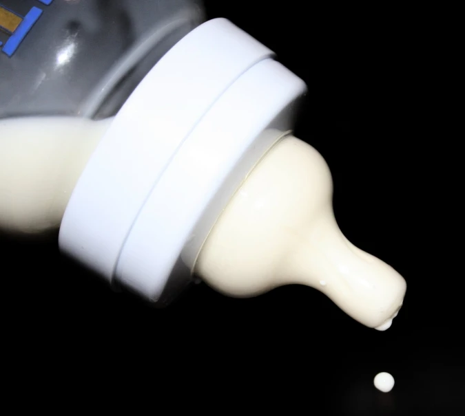 a bottle is pouring milk into another one