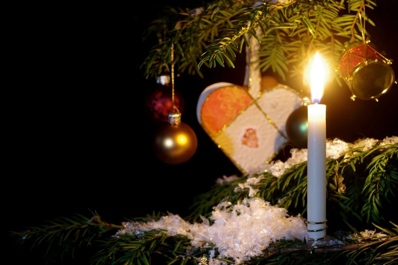 christmas ornaments and candle are shown with baubles