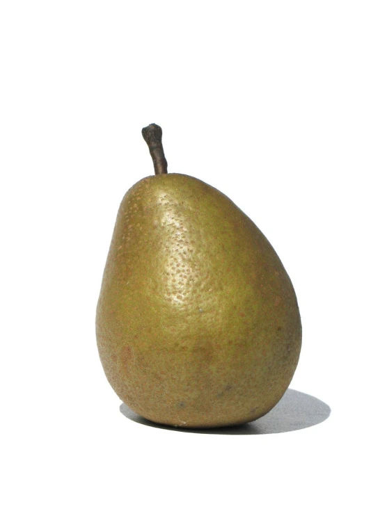 a large golden pear on white surface with a shadow