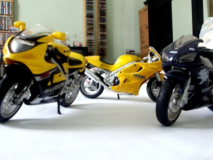 two yellow motorcycles parked next to each other on a floor