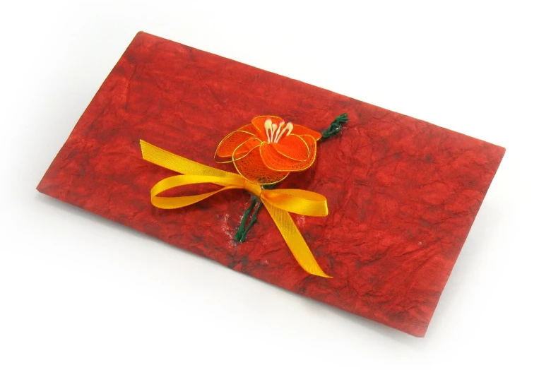 a flower with yellow ribbon on a red cloth