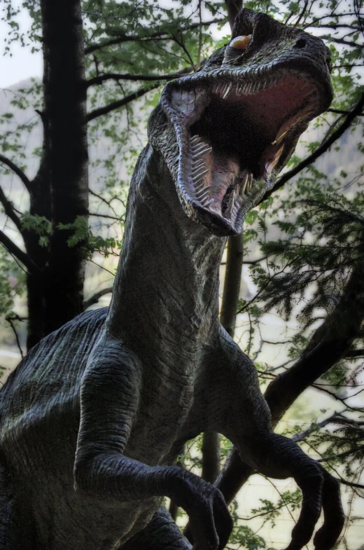 a dinosaur statue standing in front of a tree