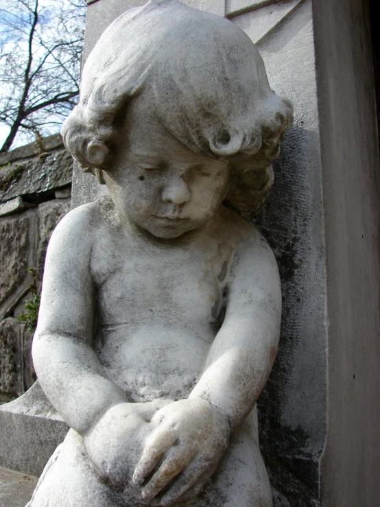 an old statue sitting next to a stone wall