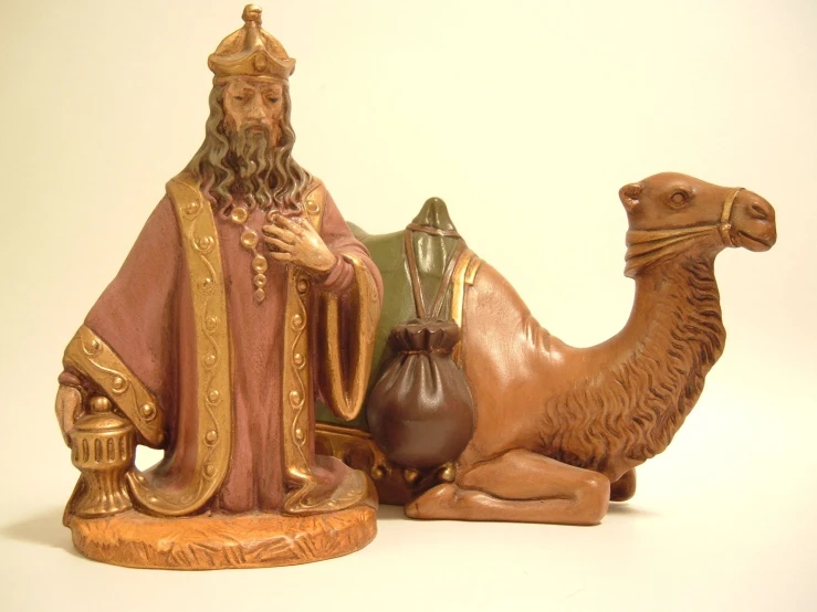 three different colored statues of wise men sitting around a camel
