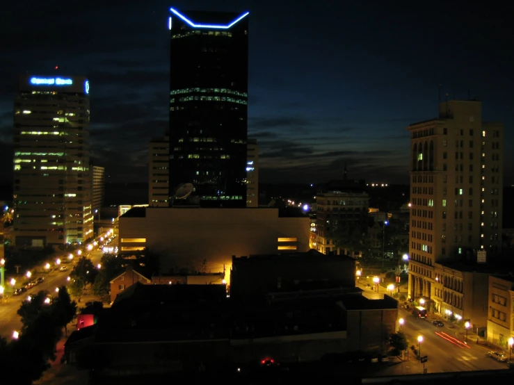 the skyline at night, including a modern skyscr with blue neon lights, is lit up