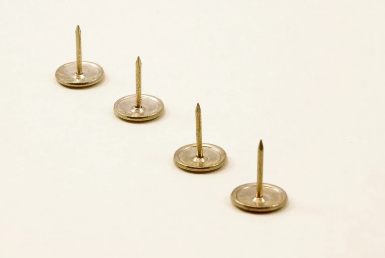 three metal nails sticking out of some small metal disks