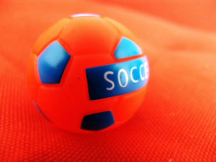 a soccer ball is on an orange fabric background