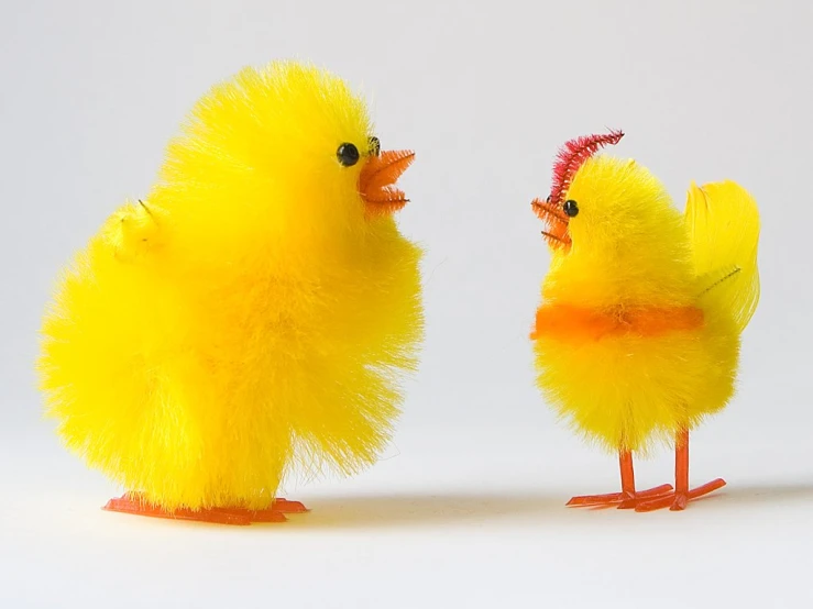 a small yellow toy chicken standing next to a smaller one