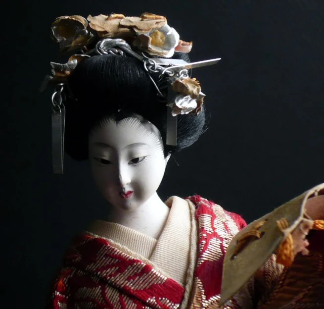 a dolls head holding a japanese knife with other doll's hair