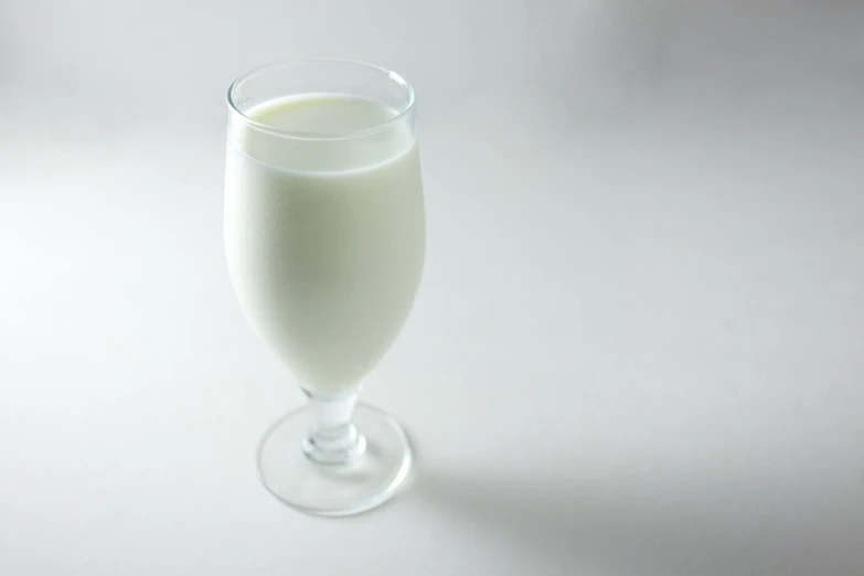 a glass full of white milk on a white table