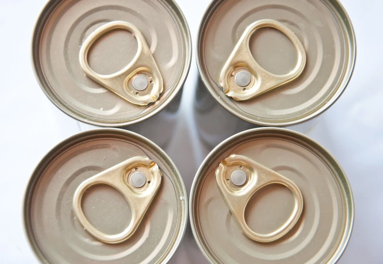 four open soda cans that have scissors in them