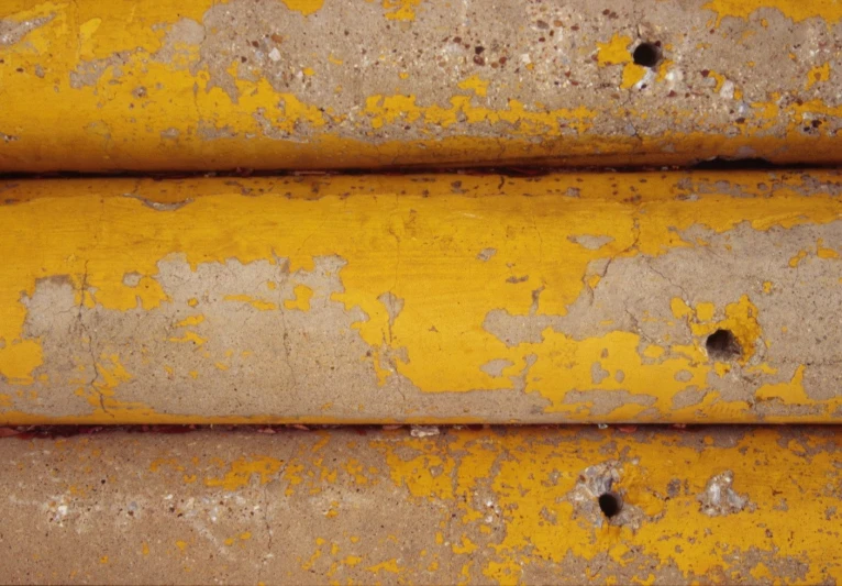 closeup of yellow pipes with s and rivets on them