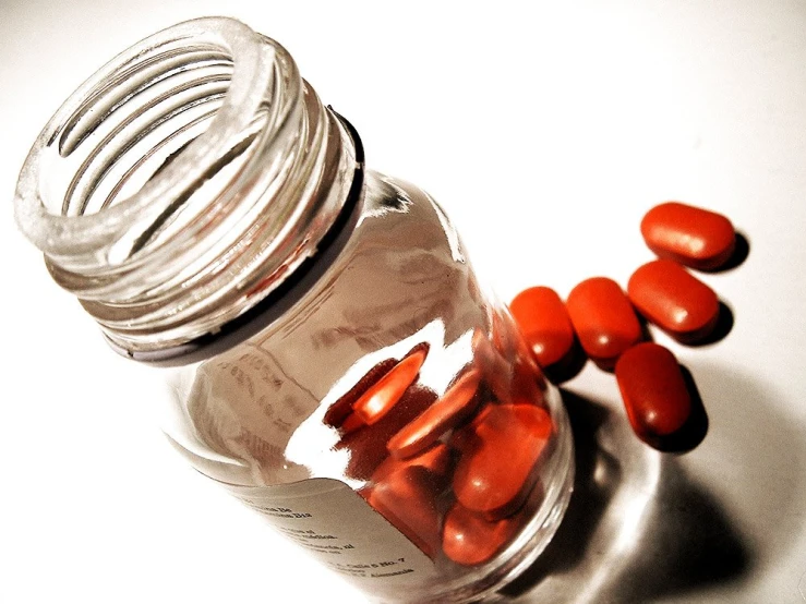 several pills scattered on top of a glass bottle