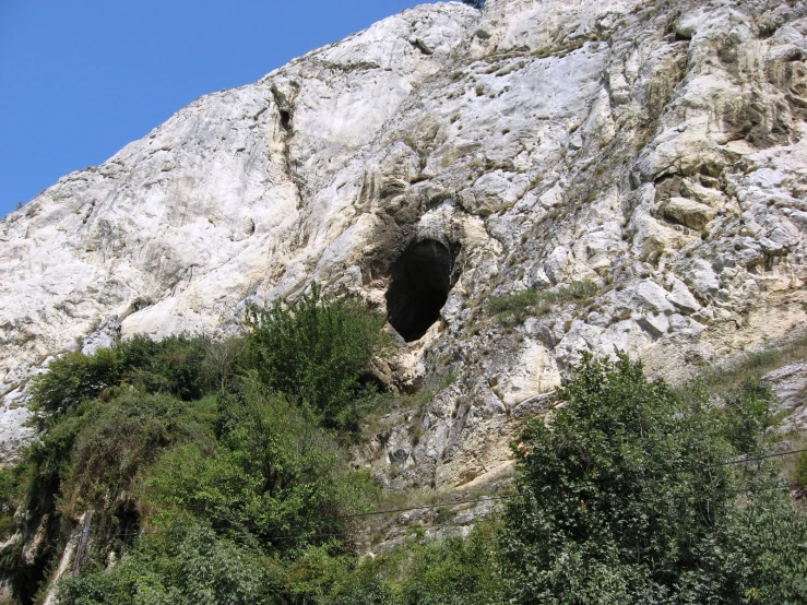 the side of a mountain shows a small tunnel in the rock