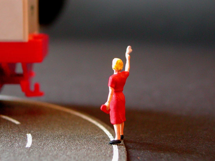 a toy lady stands on a paved road