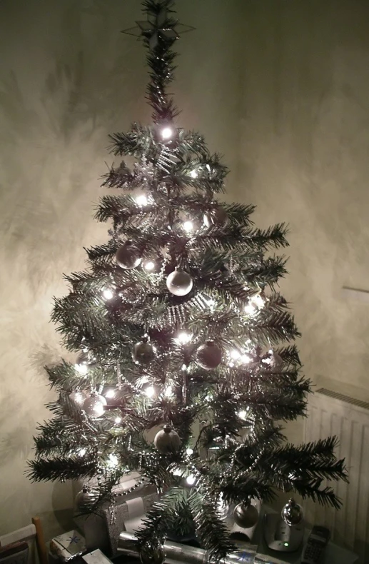 a shiny christmas tree in a room with an electric fireplace