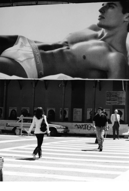 man  and ed walks down the street in front of a billboard