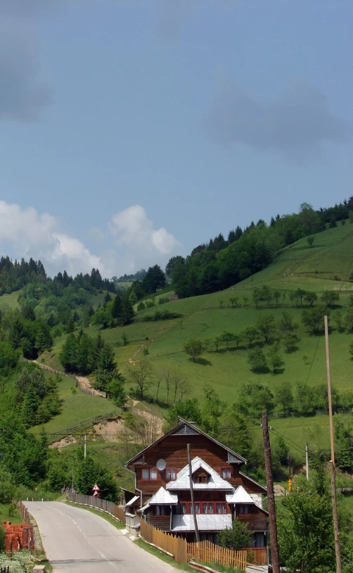 a view of a rural road that leads to a two story house