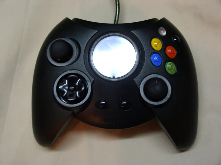 a black video game controller with colored ons