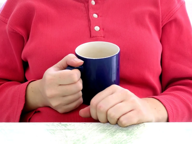 a person holding a cup while sitting down