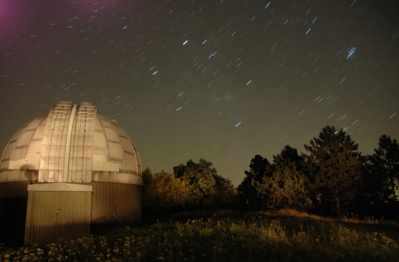 the night sky with stars above a large dome