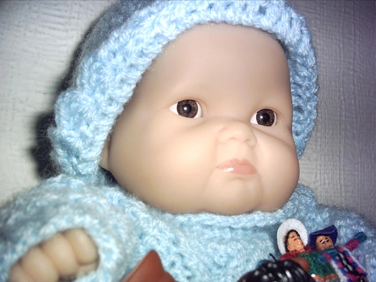 a small doll is wearing a blue sweater